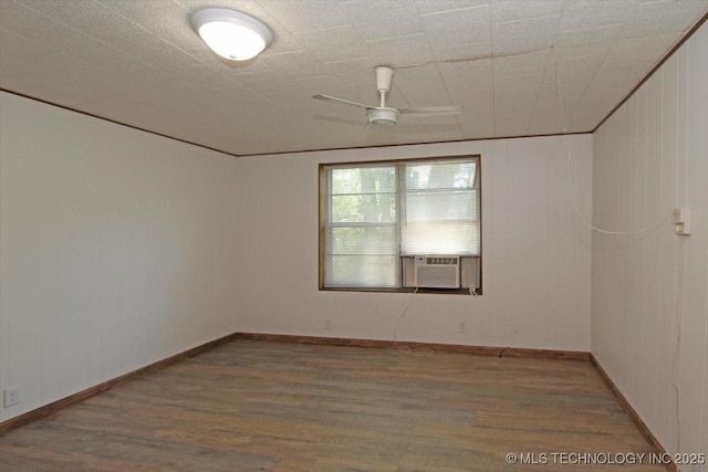 unfurnished room featuring cooling unit, wood finished floors, and baseboards