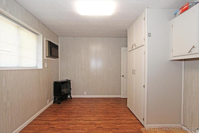 unfurnished room featuring a wood stove and wood finished floors
