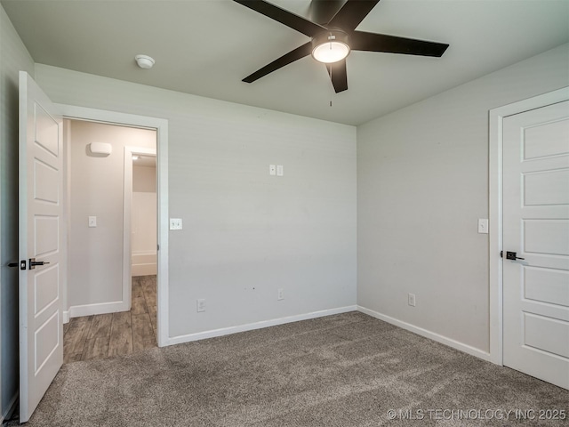 carpeted empty room featuring ceiling fan, baseboards, and a smoke detector
