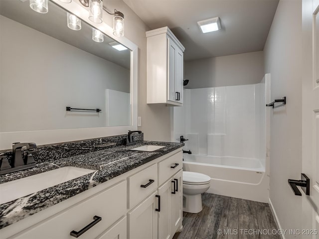 bathroom featuring wood finished floors, toilet, double vanity, and shower / bathtub combination