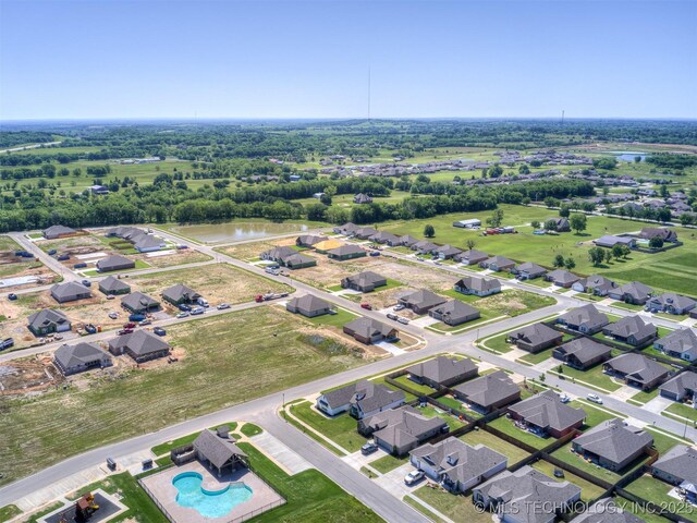 aerial view of property and surrounding area featuring nearby suburban area, a pool area, and a nearby body of water