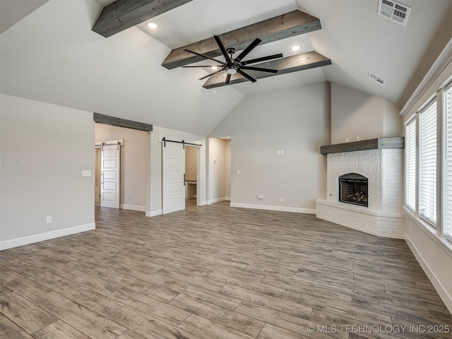 unfurnished living room with a barn door, ceiling fan, wood finished floors, baseboards, and recessed lighting