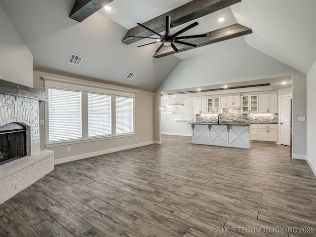 unfurnished living room featuring ceiling fan, a brick fireplace, wood finished floors, baseboards, and recessed lighting