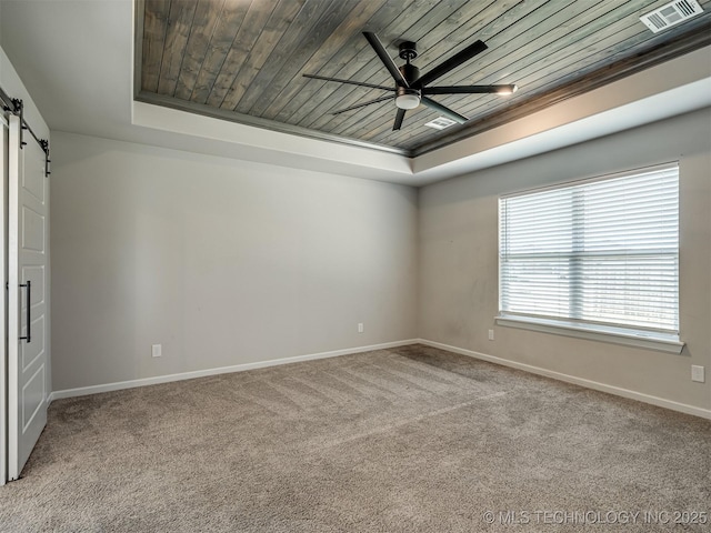 carpeted spare room featuring a raised ceiling, a barn door, a ceiling fan, baseboards, and wood ceiling