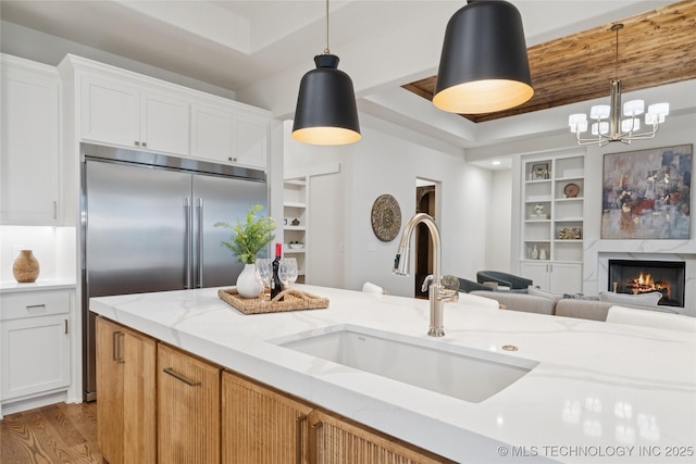 2607 E 135th Dr S, Bixby, OK 74008 - kitchen featuring wood finished floors, a chandelier, light stone countertops, built in shelves, and white cabinetry