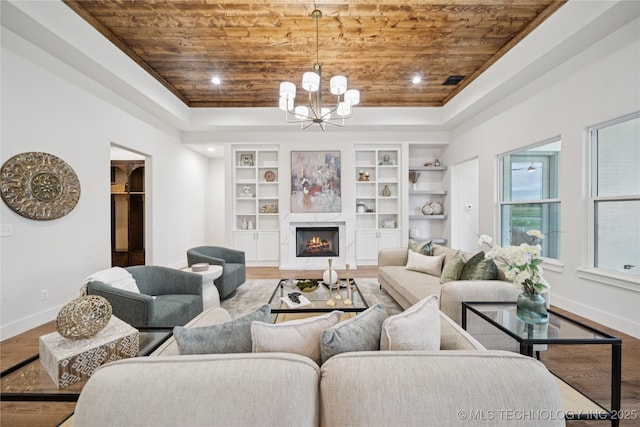 2607 E 135th Dr S, Bixby, OK 74008 - living room featuring wood ceiling, wood finished floors, a chandelier, built in features, and a lit fireplace