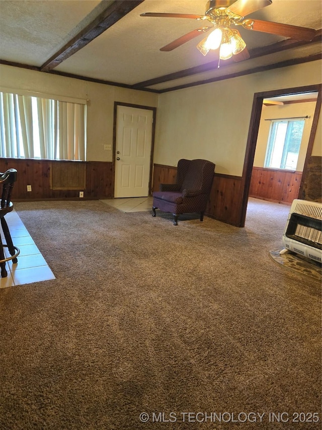 living area featuring heating unit, wainscoting, carpet floors, wood walls, and ceiling fan