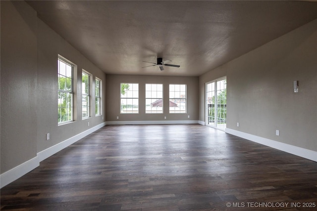 100 E Broadway, Sulphur, OK 73086 - unfurnished room with healthy amount of natural light, dark wood-type flooring, a ceiling fan, and baseboards