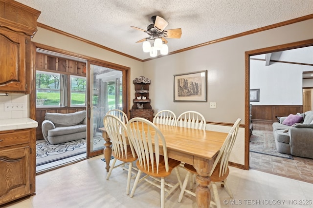 2956 E 69th St, Tulsa, OK 74136 - dining room with crown molding, a ceiling fan, a textured ceiling, and wooden walls