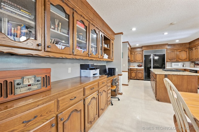 2956 E 69th St, Tulsa, OK 74136 - kitchen with high end black refrigerator, white microwave, brown cabinets, glass insert cabinets, and a textured ceiling