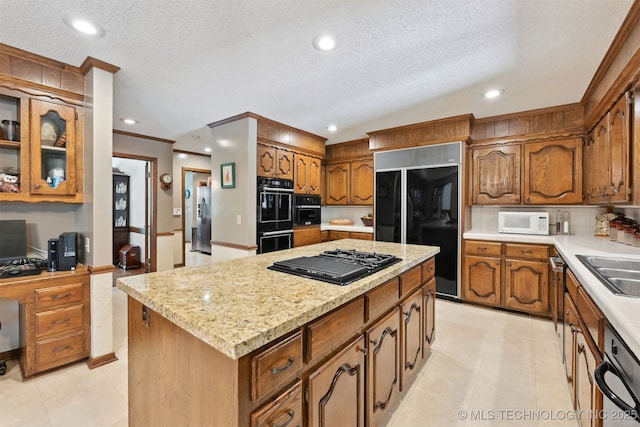 2956 E 69th St, Tulsa, OK 74136 - kitchen with black appliances, a center island, brown cabinets, a desk, and a textured ceiling