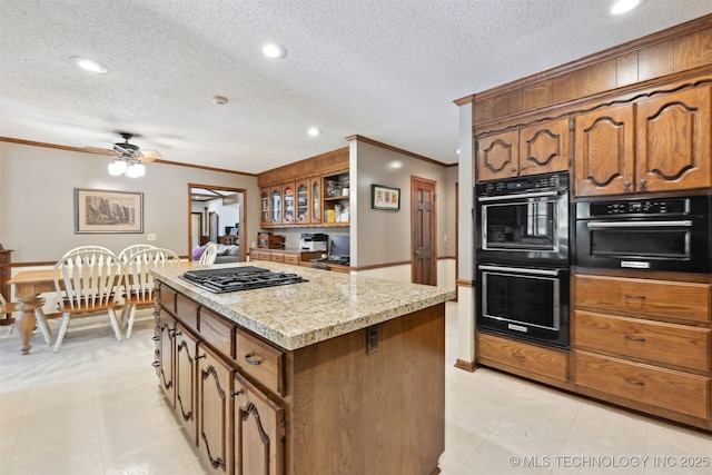 2956 E 69th St, Tulsa, OK 74136 - kitchen featuring stainless steel gas cooktop, ornamental molding, a kitchen island, brown cabinetry, and a ceiling fan