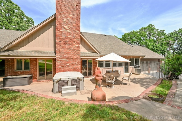 2956 E 69th St, Tulsa, OK 74136 - back of house with board and batten siding, a chimney, roof with shingles, and a patio