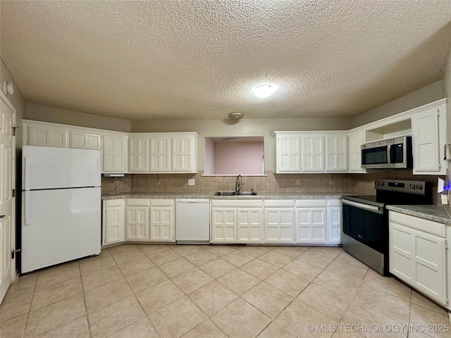 kitchen with appliances with stainless steel finishes, a sink, backsplash, white cabinets, and a textured ceiling