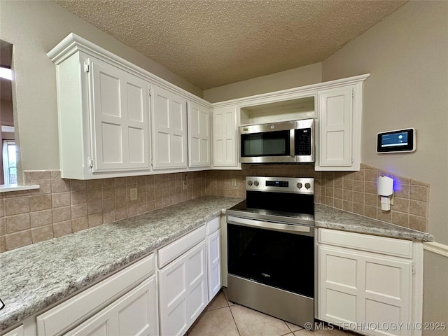 kitchen with stainless steel appliances, white cabinetry, tasteful backsplash, a textured ceiling, and light tile patterned floors