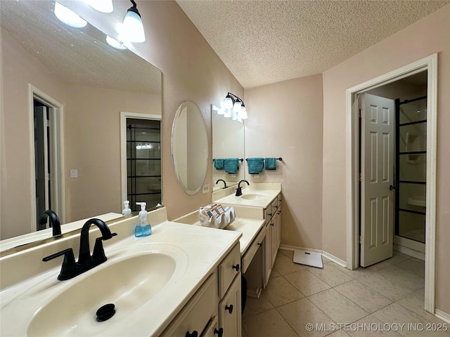 full bath featuring a textured ceiling, tile patterned flooring, two vanities, and baseboards