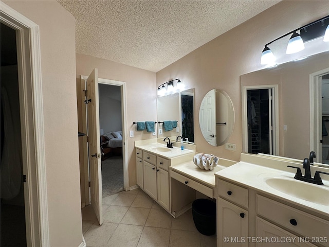 ensuite bathroom featuring a textured ceiling, two vanities, and tile patterned flooring