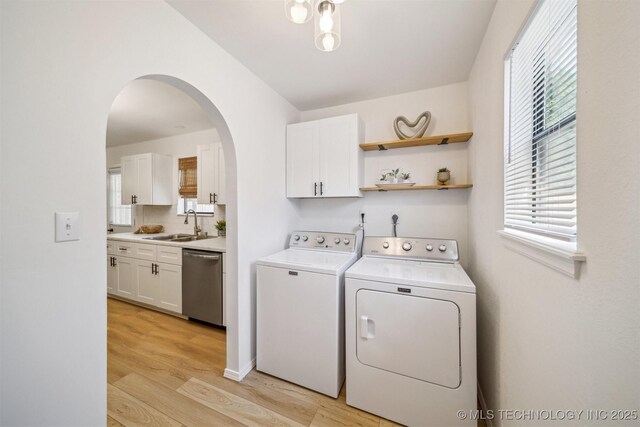 1010 S Wewoka Ave, Claremore, OK 74017 - laundry room featuring washer and dryer, cabinet space, light wood-type flooring, arched walkways, and healthy amount of natural light