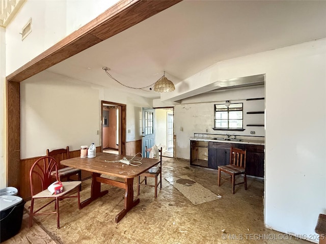 dining space featuring a wainscoted wall and wood walls