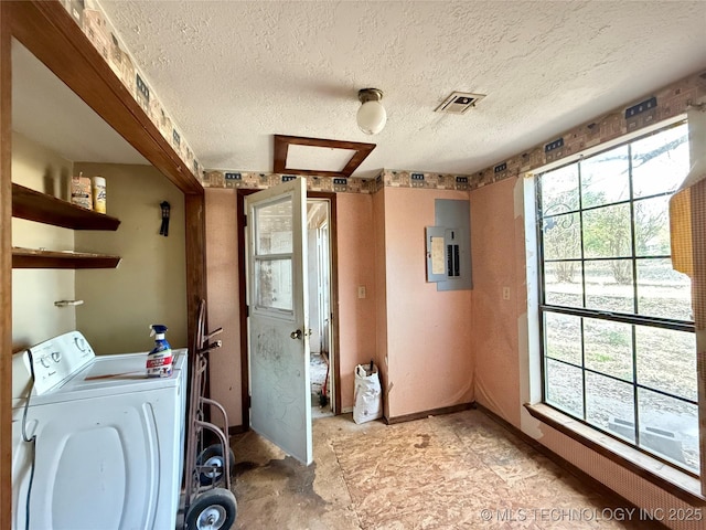 clothes washing area featuring washer / dryer, a textured ceiling, plenty of natural light, and electric panel