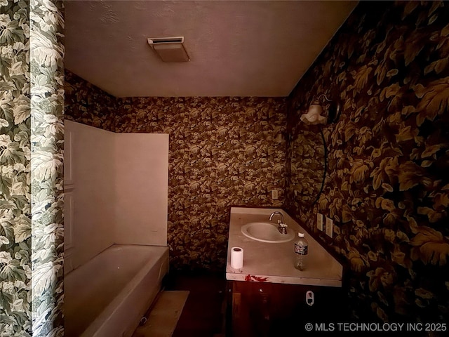 bathroom featuring wallpapered walls, a tub, and vanity