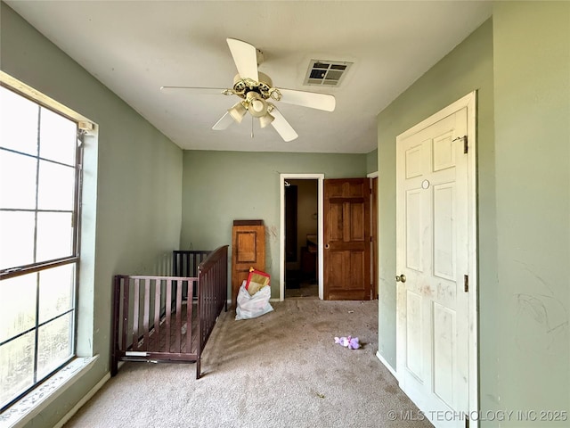 unfurnished bedroom featuring multiple windows, carpet, and ceiling fan