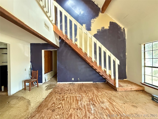 unfurnished living room with a high ceiling and stairs