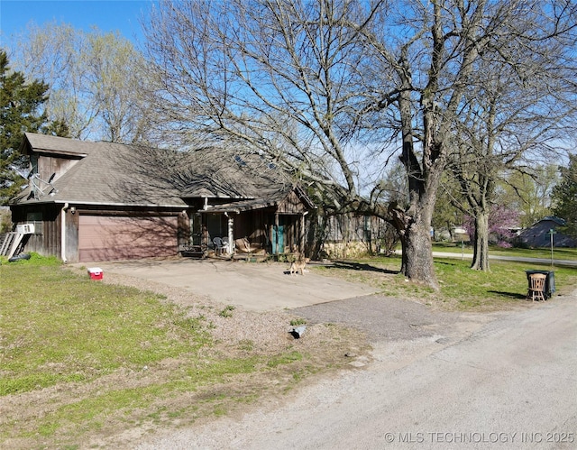 view of property hidden behind natural elements with dirt driveway, a garage, and a front yard