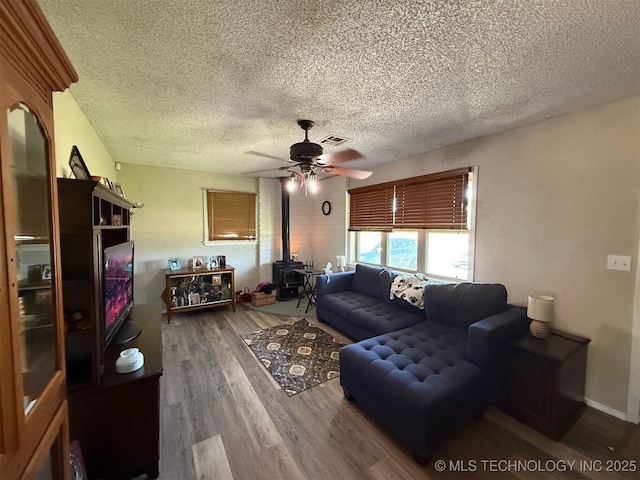 15760 Briar Rd, Morris, OK 74445 - living room featuring a wood stove, a textured ceiling, wood finished floors, and a ceiling fan
