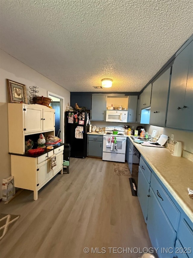 15760 Briar Rd, Morris, OK 74445 - kitchen featuring black appliances, a textured ceiling, light wood finished floors, light countertops, and blue cabinetry