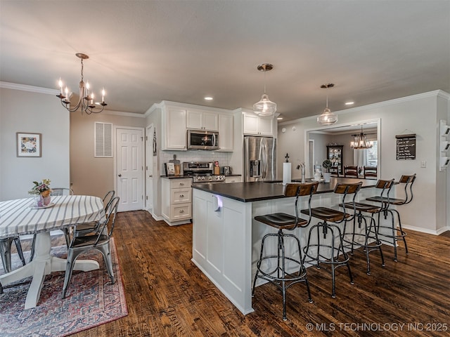 5517 E 101st Pl, Tulsa, OK 74137 - kitchen with appliances with stainless steel finishes, a chandelier, dark countertops, dark wood-style flooring, and a breakfast bar area