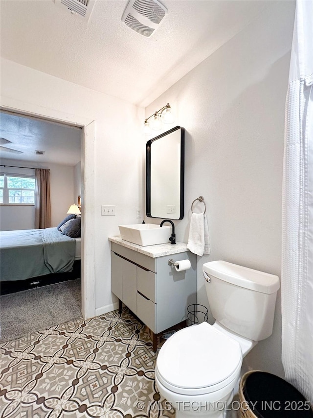 602 S Elm St, Muldrow, OK 74948 - ensuite bathroom with toilet, vanity, a textured ceiling, and baseboards