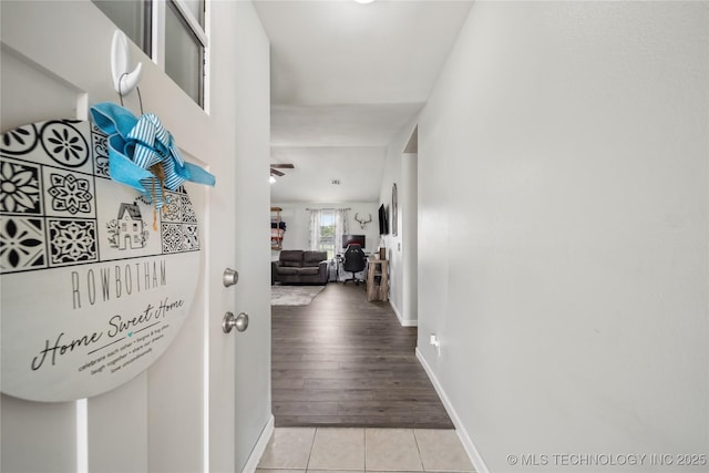 corridor featuring baseboards and light tile patterned floors