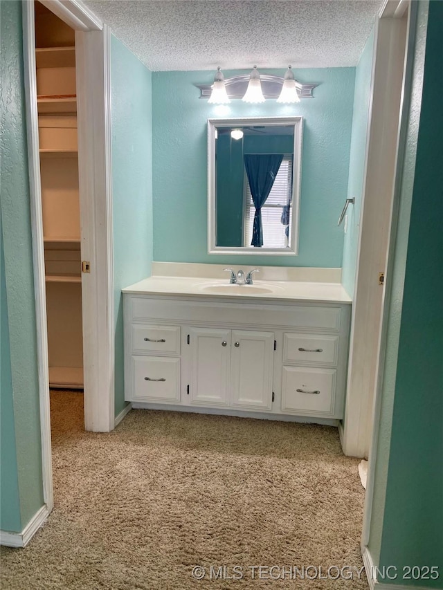 3164 S 101st E Ave Unit 801, Tulsa, OK 74146 - bathroom featuring vanity, a textured ceiling, a walk in closet, and a textured wall