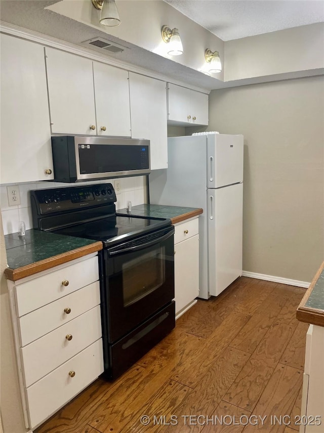 3164 S 101st E Ave Unit 801, Tulsa, OK 74146 - kitchen with stainless steel microwave, black range with electric stovetop, dark wood-style floors, white cabinetry, and dark countertops