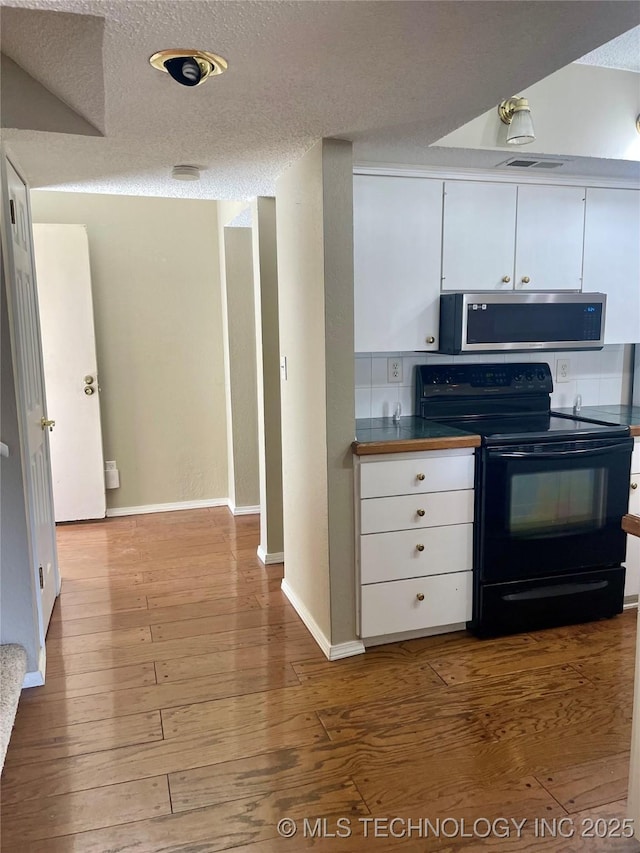 3164 S 101st E Ave Unit 801, Tulsa, OK 74146 - kitchen with stainless steel microwave, electric range, white cabinets, hardwood / wood-style floors, and a textured ceiling