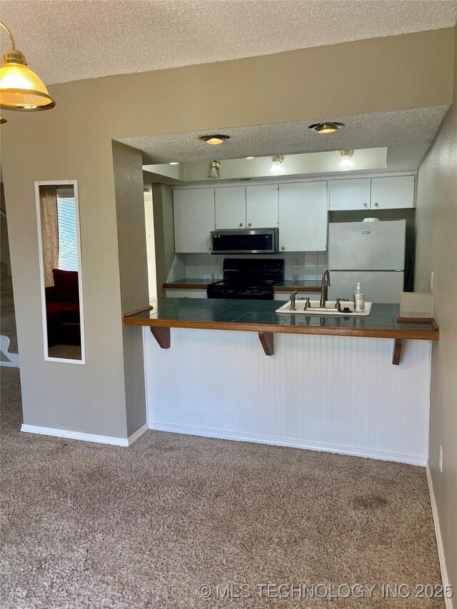 3164 S 101st E Ave Unit 801, Tulsa, OK 74146 - kitchen with black electric range, freestanding refrigerator, a sink, stainless steel microwave, and a textured ceiling