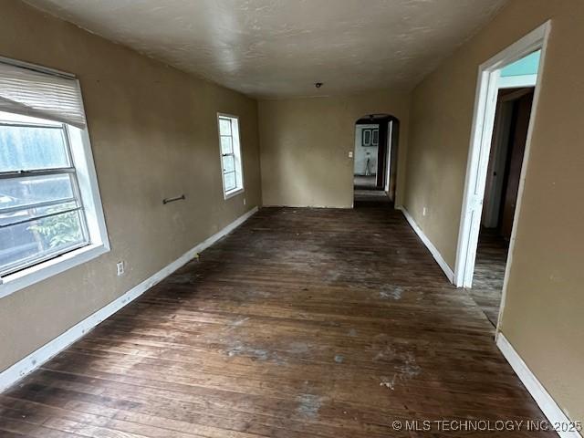 708 S 1st, Davis, OK 73030 - empty room featuring arched walkways, wood-type flooring, and baseboards