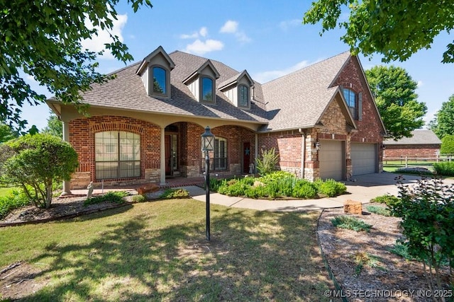 view of front of home featuring brick siding, a front yard, and a shingled roof