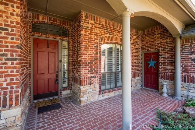 doorway to property featuring brick siding and a porch