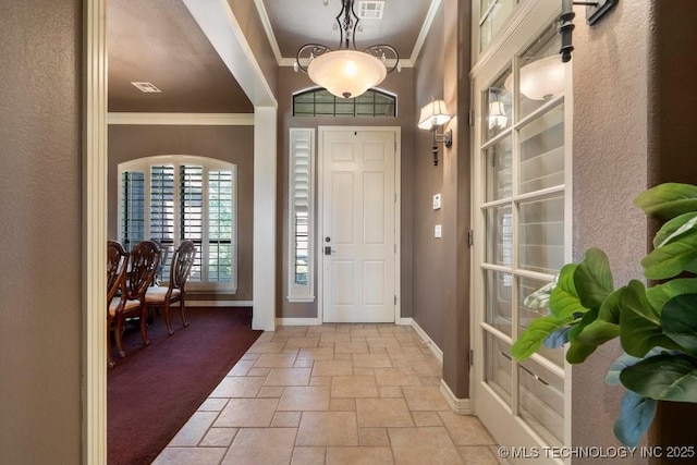 foyer with crown molding, stone tile flooring, and baseboards