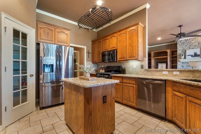 kitchen with appliances with stainless steel finishes, crown molding, tasteful backsplash, a kitchen island, and light stone counters