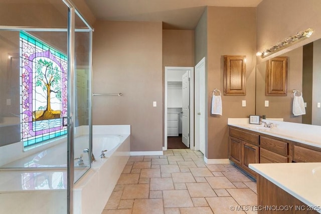 full bathroom with vanity, a garden tub, stone tile floors, baseboards, and a stall shower