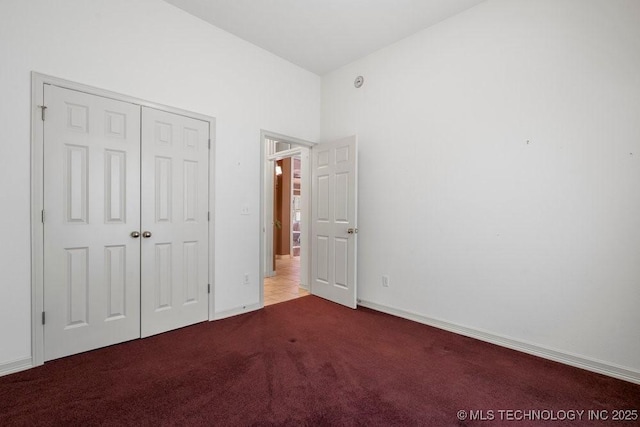 unfurnished bedroom with carpet flooring, a closet, and baseboards
