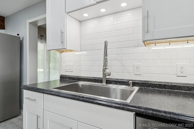 kitchen with freestanding refrigerator, a sink, white cabinets, tasteful backsplash, and recessed lighting