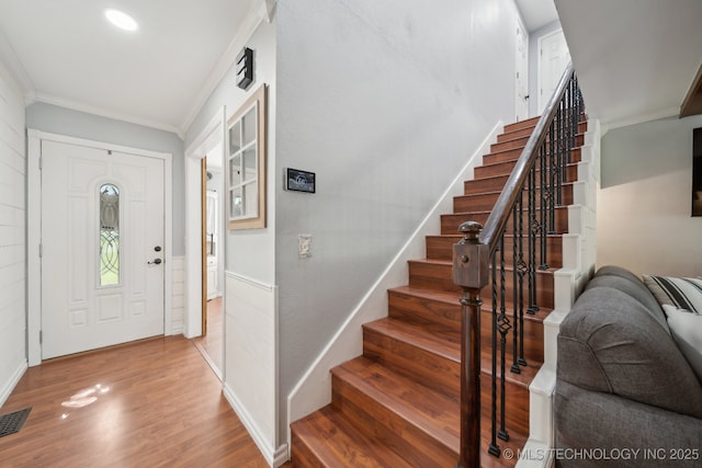 entryway featuring ornamental molding, stairs, wood finished floors, and baseboards
