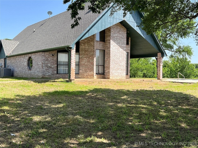 514 Lakeshore St, Durant, OK 74701 - back of house with cooling unit, brick siding, a yard, and roof with shingles