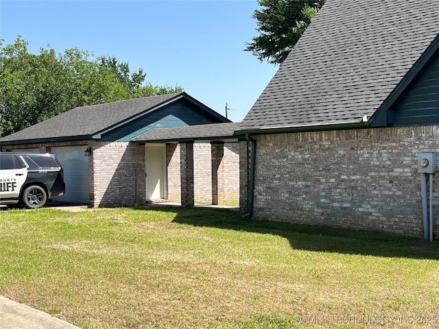514 Lakeshore St, Durant, OK 74701 - view of side of home featuring an attached garage, roof with shingles, a lawn, and brick siding