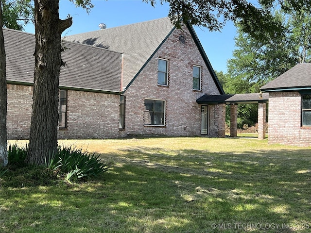 514 Lakeshore St, Durant, OK 74701 - rear view of house with brick siding, a lawn, and a shingled roof