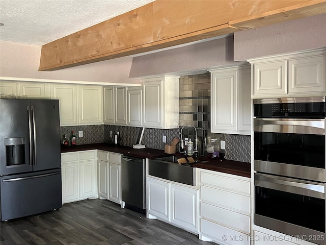 514 Lakeshore St, Durant, OK 74701 - kitchen featuring stainless steel appliances, a sink, dark countertops, backsplash, and dark wood-style floors
